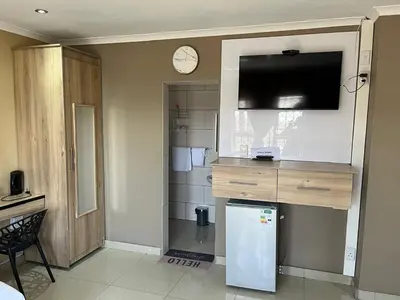 a kitchen with a refrigerator and a clock on the wall at Zonke Bonke Guest House in Burgersfort