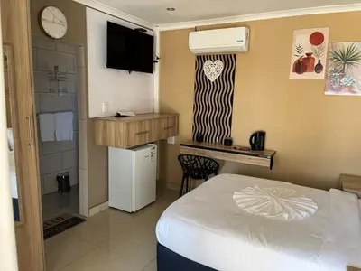 a bedroom with a bed and a desk and a tv at Zonke Bonke Guest House in Burgersfort