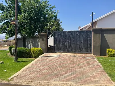 a brick driveway with a gate in front of a house at Zonke Bonke Guest House in Burgersfort