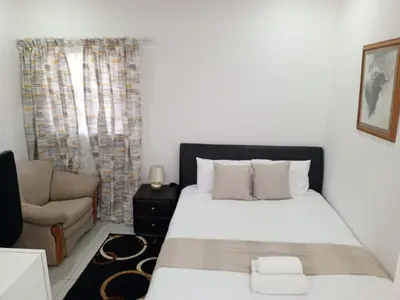 a bedroom with a large bed and a couch at Millenium Manor in Centurion