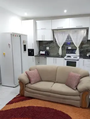 a living room with a couch and a kitchen at Millenium Manor in Centurion
