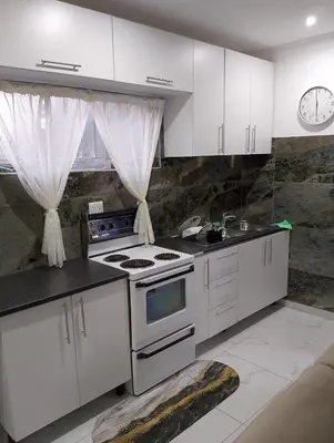 a kitchen with white cabinets and a stove top oven at Millenium Manor in Centurion