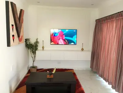 a living room with a tv on a wall at Millenium Manor in Centurion