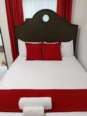 a bedroom with a white bed with red pillows at Millenium Manor in Centurion