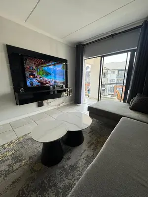 a living room with two tables and a flat screen tv at Lagoon lounge - The blyde crystal Lagoon in Pretoria