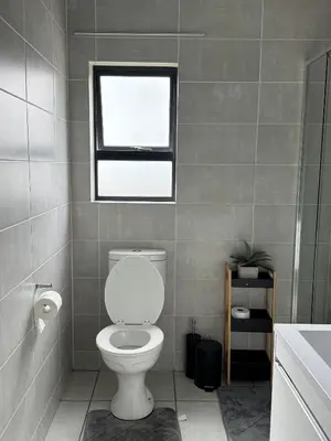 a bathroom with a white toilet and a window at Lagoon lounge - The blyde crystal Lagoon in Pretoria