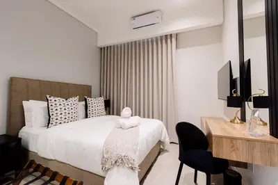 a bedroom with a white bed with a desk and a chair at 532 Menlyn Maine in Pretoria
