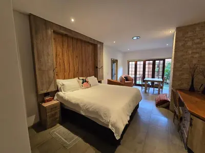 a bedroom with a bed and a table in a room at Lombard Manor in Pretoria