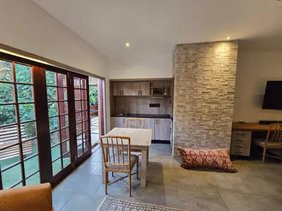a living room with a table and a brick wall at Lombard Manor in Pretoria