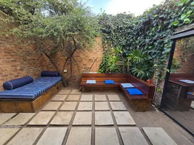 a patio with two wooden benches and a brick wall at Lombard Manor in Pretoria