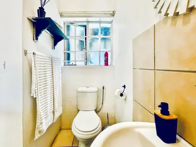 a bathroom with a toilet and a sink and a window at Tiny Home in Centurion