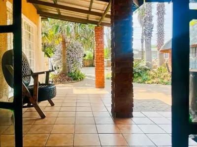 a porch with a bench and palm trees at Tiny Home in Centurion