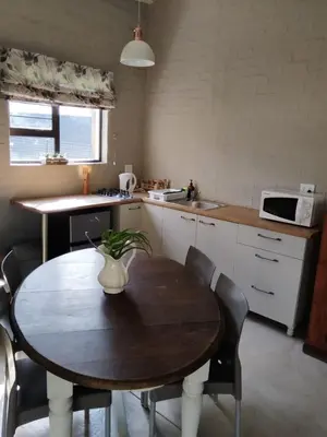a kitchen with a wooden table with chairs and a microwave at Aloe Thorn Self Catering in White River