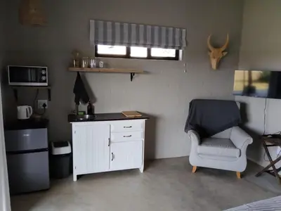 a small room with a chair and a white cabinet at Aloe Thorn Self Catering in White River