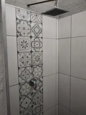 a room with a tile wall with a shower with a water nozzle at Aloe Thorn Self Catering in White River