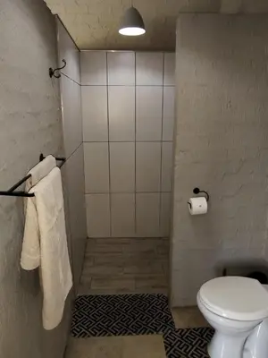a bathroom with a toilet and a shower with towels at Aloe Thorn Self Catering in White River