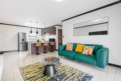 a living room with a green couch and a table at TruVela Executive Apartments - Midrand in Midrand
