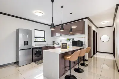 a kitchen with a counter and two stools at TruVela Executive Apartments - Midrand in Midrand