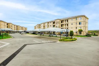 a parking lot in front of a large building at TruVela Executive Apartments - Midrand in Midrand