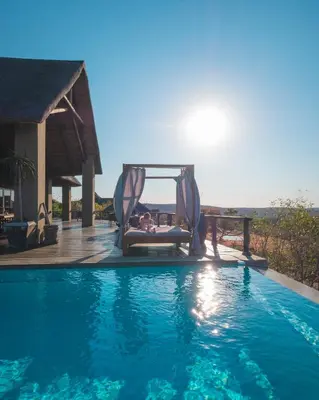 a person sitting in a chair next to a swimming pool at 57 Waterberg in Welgevonden Game Reserve
