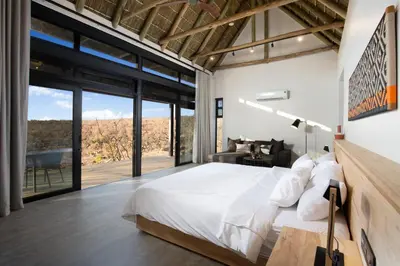 a bedroom with a large bed and large windows at 57 Waterberg in Welgevonden Game Reserve