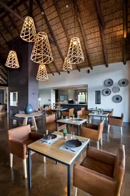 a restaurant with tables and chairs and chandeliers at 57 Waterberg in Welgevonden Game Reserve