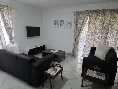 a living room with a black couch and a tv at The Pot in Pretoria