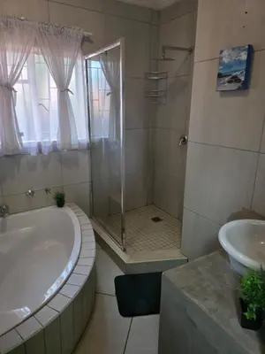 a bathroom with a tub and a shower and a sink at The Pot in Pretoria