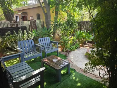 two blue chairs and a table in a garden at The Pot in Pretoria
