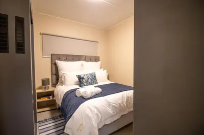 a bedroom with a large bed with a blue blanket at Waterfall Ridge Luxurious Apartment 2 Backup Power in Midrand