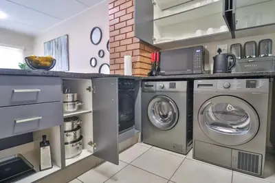 a kitchen with two washer and dryer in it at Waterfall Ridge Luxurious Apartment 2 Backup Power in Midrand