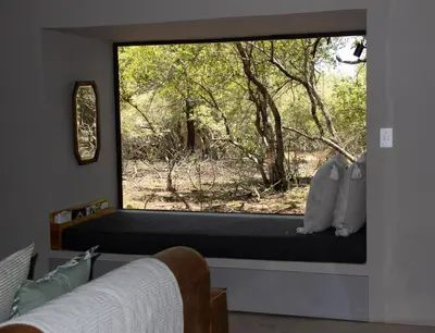 a window seat in a bedroom with a view of the woods at Ratel Katel in Marloth Park