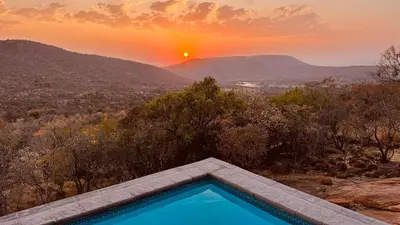 a swimming pool with a sunset in the background at 19 on Idwala, Mabalingwe Game Reserve in Warmbaths