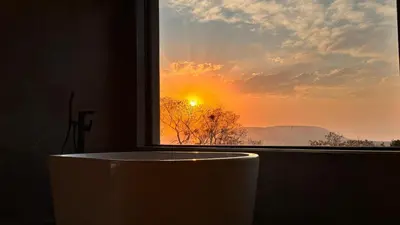 a window with a tub in front of a sunset at 19 on Idwala, Mabalingwe Game Reserve in Warmbaths