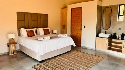 a bedroom with a large bed and a sink at 19 on Idwala, Mabalingwe Game Reserve in Warmbaths