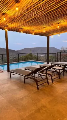 a group of picnic tables under a pavilion with a pool at 19 on Idwala, Mabalingwe Game Reserve in Warmbaths