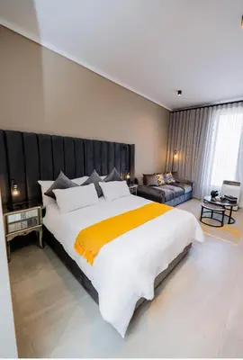 a large bedroom with a large bed and a couch at Trilogy studio apartment 831 in Pretoria