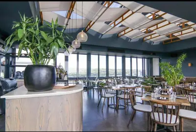 a restaurant with tables and chairs and large windows at Trilogy studio apartment 831 in Pretoria