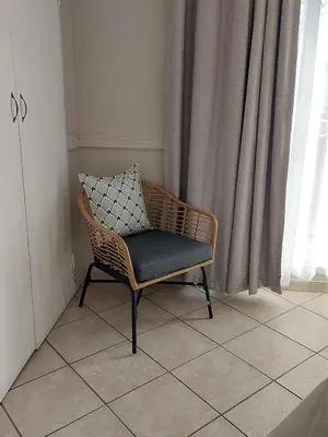 a wicker chair sitting on a tiled floor in front of a window at Eight Martjie Guesthouse in Brits