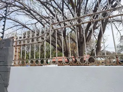 a metal fence with a tree in the background at Eight Martjie Guesthouse in Brits