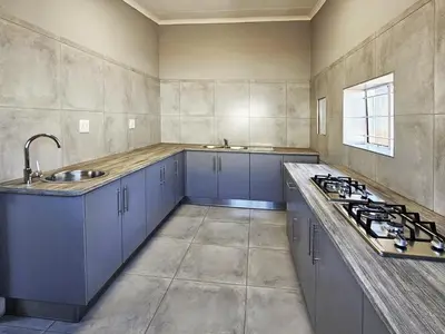 a large kitchen with blue cabinets and a sink at Beds Inn Midrand in Midrand