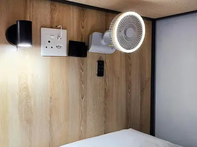 a bedroom with a fan on a wooden wall at Beds Inn Midrand in Midrand