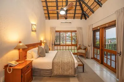 a bedroom with a large bed and a balcony at Kruger Park Lodge Unit No 304 in Hazyview
