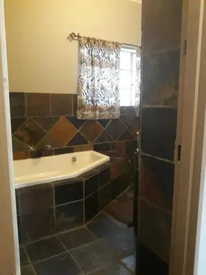 a bathroom with a tub and a window at African Silhouette Guesthouse in Benoni