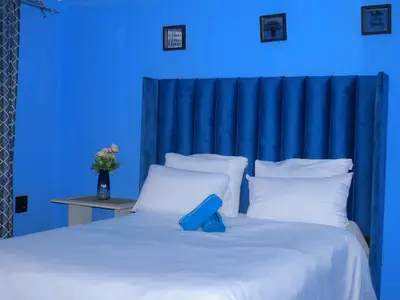 a blue room with a large bed with white pillows at Mahlako Guest Lodge in Polokwane
