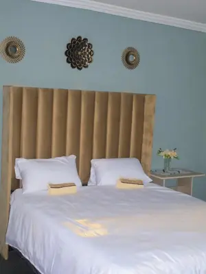 a bedroom with a large white bed with two pillows at Mahlako Guest Lodge in Polokwane