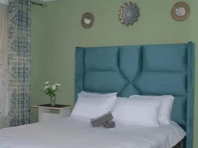 a bed with a blue head board and white pillows at Mahlako Guest Lodge in Polokwane