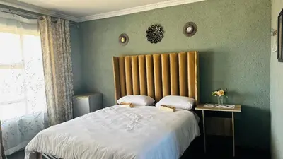 a bedroom with a large bed with a wooden headboard at Mahlako Guest Lodge in Polokwane
