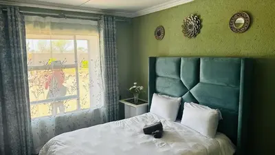 a bedroom with a bed with a blue headboard and a window at Mahlako Guest Lodge in Polokwane