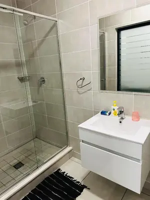 a bathroom with a shower and a sink and a mirror at The Blyde Pretoria in Pretoria